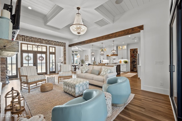 living room featuring hardwood / wood-style floors, french doors, a chandelier, and beam ceiling