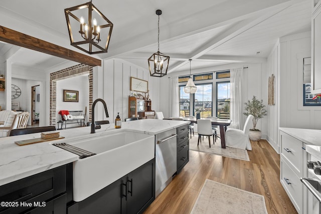 kitchen featuring light stone counters, stainless steel dishwasher, pendant lighting, beam ceiling, and light hardwood / wood-style floors