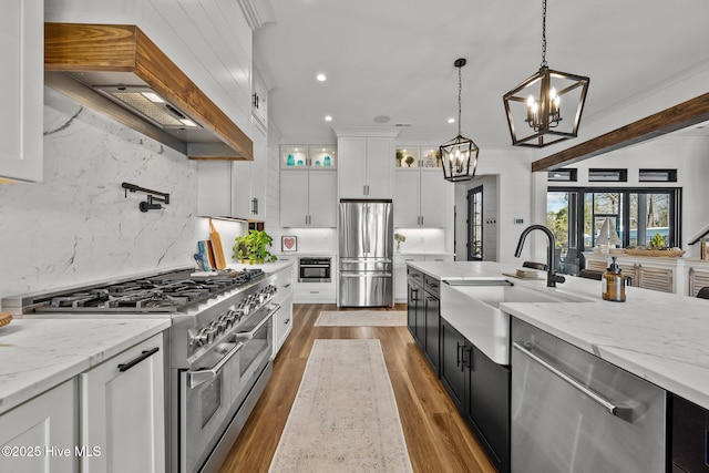 kitchen with white cabinetry, sink, hanging light fixtures, stainless steel appliances, and decorative backsplash