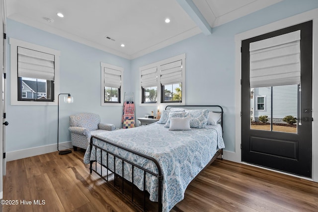 bedroom with beam ceiling, multiple windows, wood-type flooring, and ornamental molding