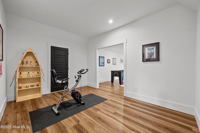 exercise room featuring wood-type flooring and vaulted ceiling