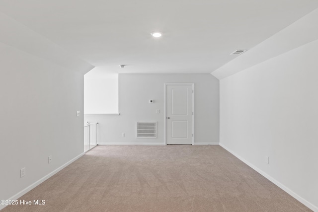 additional living space featuring vaulted ceiling and light colored carpet