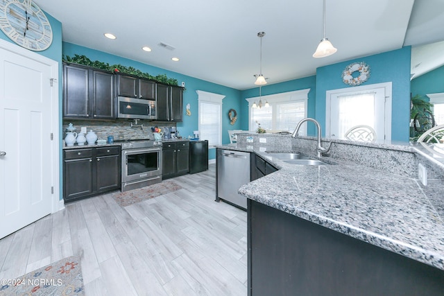 kitchen with dark brown cabinetry, sink, tasteful backsplash, decorative light fixtures, and appliances with stainless steel finishes