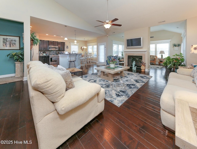 living room with dark wood-style flooring, ceiling fan, visible vents, and vaulted ceiling