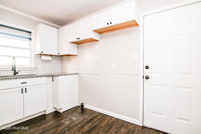 kitchen with tasteful backsplash, dark wood-type flooring, sink, stone counters, and white cabinets