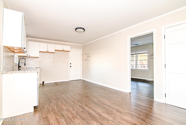 interior space with hardwood / wood-style floors, sink, decorative backsplash, light stone countertops, and white cabinetry