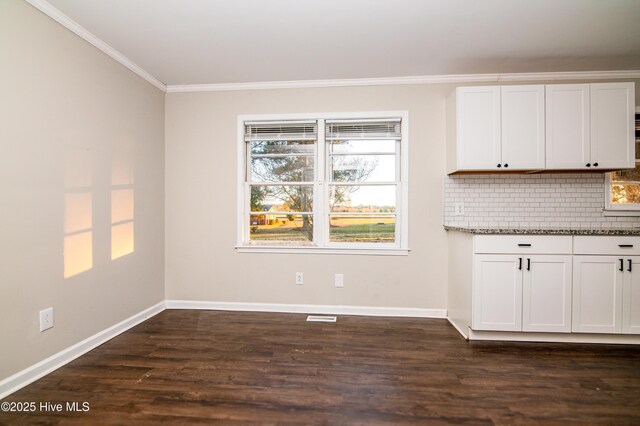 kitchen with white cabinets, decorative backsplash, dark hardwood / wood-style floors, ornamental molding, and light stone counters