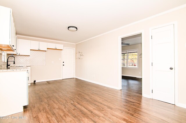 interior space featuring white cabinets, sink, light stone countertops, tasteful backsplash, and light hardwood / wood-style floors