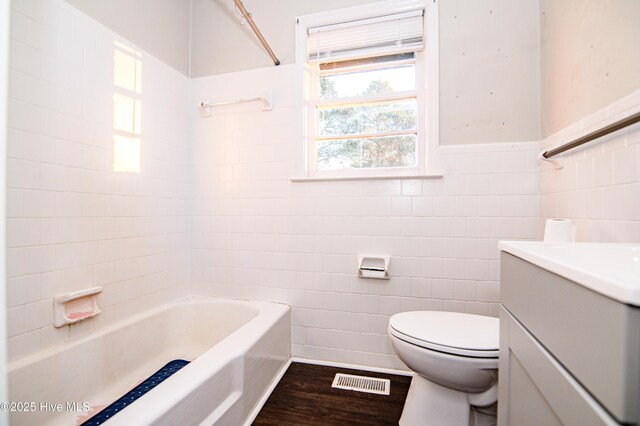 bathroom with hardwood / wood-style floors, vanity, toilet, and tile walls