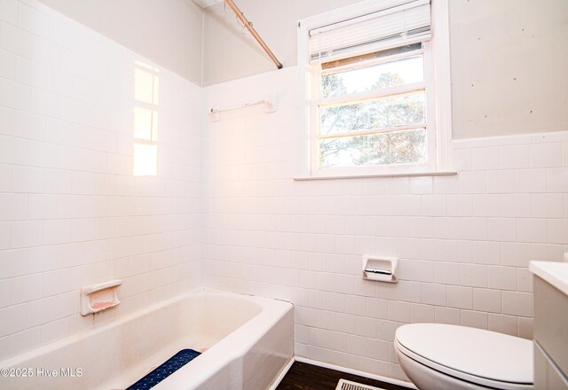 bathroom featuring hardwood / wood-style floors, shower with separate bathtub, toilet, and tile walls