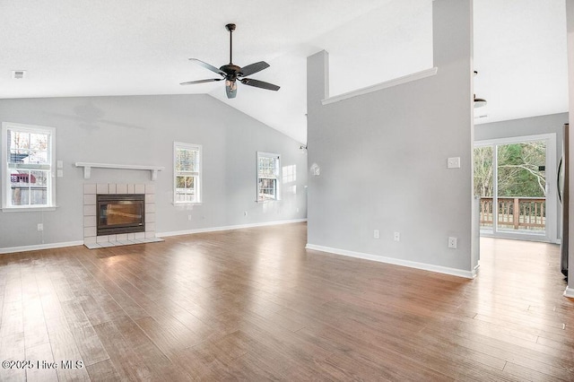 unfurnished living room with a tiled fireplace, ceiling fan, hardwood / wood-style floors, and lofted ceiling