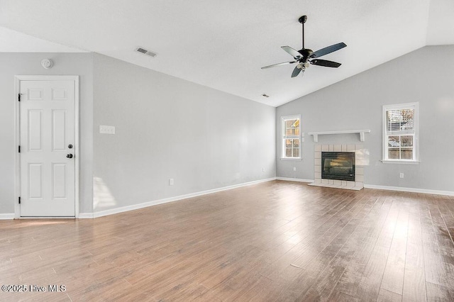 unfurnished living room featuring a tile fireplace, ceiling fan, light hardwood / wood-style flooring, and lofted ceiling