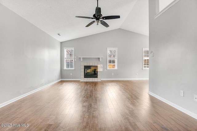 unfurnished living room featuring hardwood / wood-style floors, ceiling fan, lofted ceiling, and a fireplace