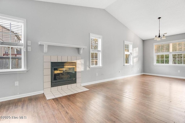 unfurnished living room with a wealth of natural light, a tile fireplace, and vaulted ceiling