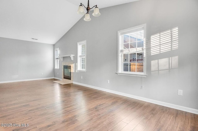 unfurnished living room featuring a fireplace, wood-type flooring, vaulted ceiling, and an inviting chandelier