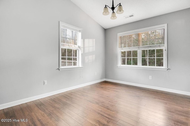 unfurnished room with wood-type flooring, lofted ceiling, and a notable chandelier