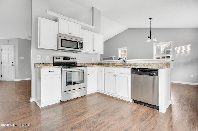 kitchen featuring white cabinets, decorative light fixtures, kitchen peninsula, and appliances with stainless steel finishes