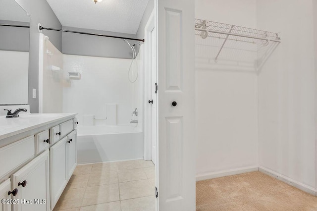 bathroom featuring tile patterned floors, vanity, a textured ceiling, and bathtub / shower combination