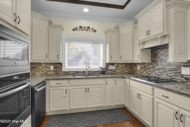 kitchen with sink, stainless steel appliances, ornamental molding, decorative backsplash, and dark stone counters