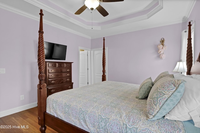 bedroom with crown molding, ceiling fan, wood-type flooring, and a tray ceiling