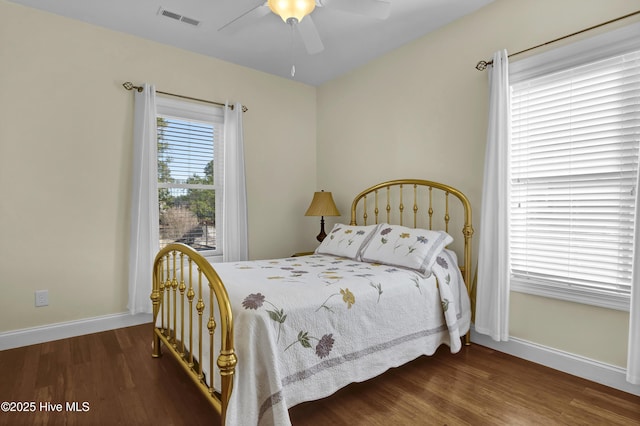 bedroom with multiple windows, dark hardwood / wood-style flooring, and ceiling fan