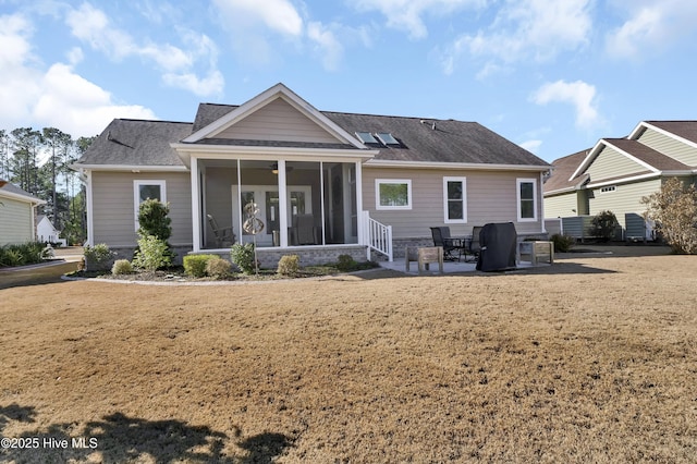 rear view of property featuring a patio, a sunroom, and a lawn