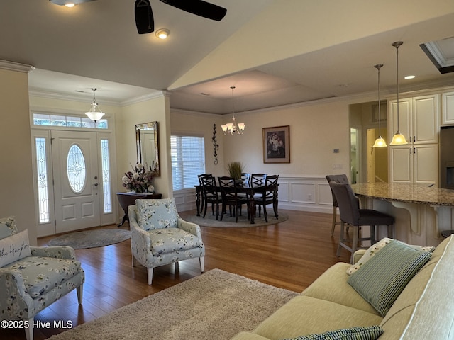 living room featuring ornamental molding, vaulted ceiling, ceiling fan with notable chandelier, and dark hardwood / wood-style flooring