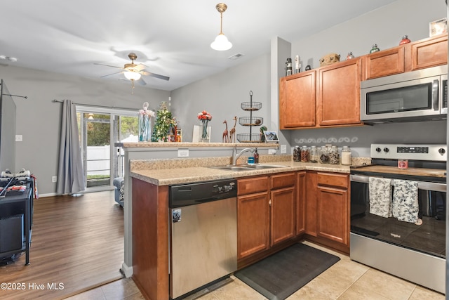 kitchen with kitchen peninsula, appliances with stainless steel finishes, ceiling fan, sink, and pendant lighting