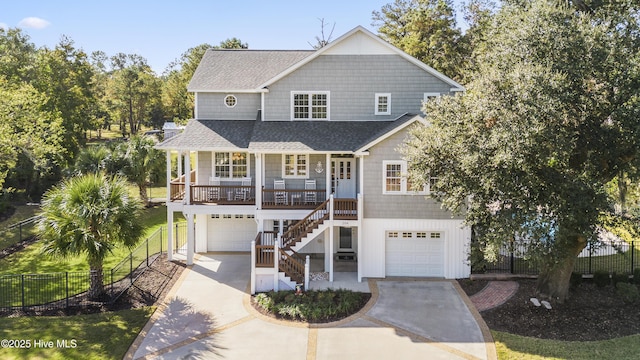 view of front of home with a porch, a shingled roof, stairway, and fence