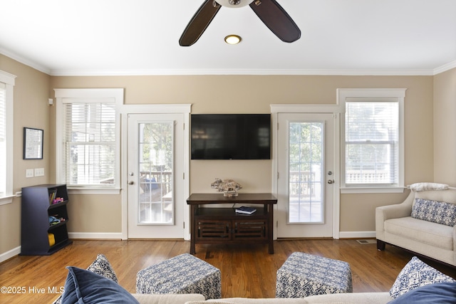 living room featuring crown molding, baseboards, ceiling fan, and wood finished floors