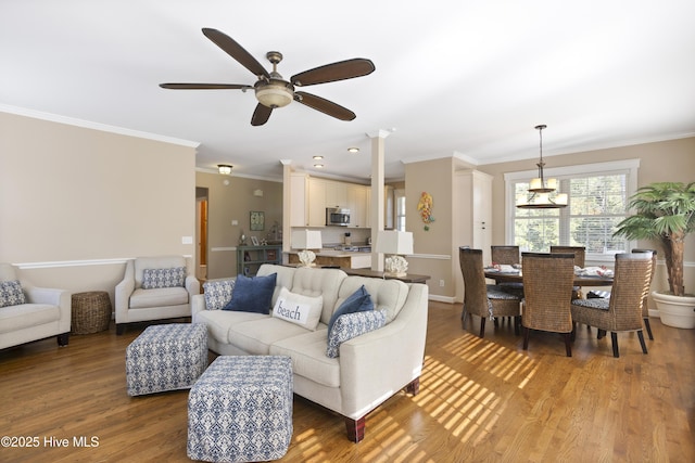 living area featuring crown molding, ceiling fan with notable chandelier, and light wood-style floors