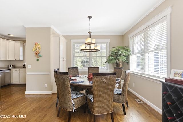 dining space with ornamental molding, light wood-type flooring, visible vents, and baseboards