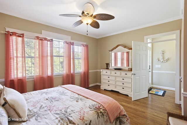 bedroom featuring a ceiling fan, crown molding, baseboards, and wood finished floors