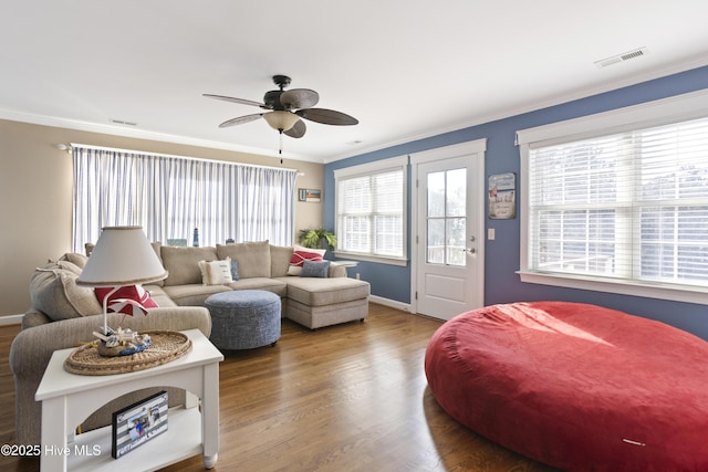 living area with ornamental molding, a ceiling fan, visible vents, and wood finished floors