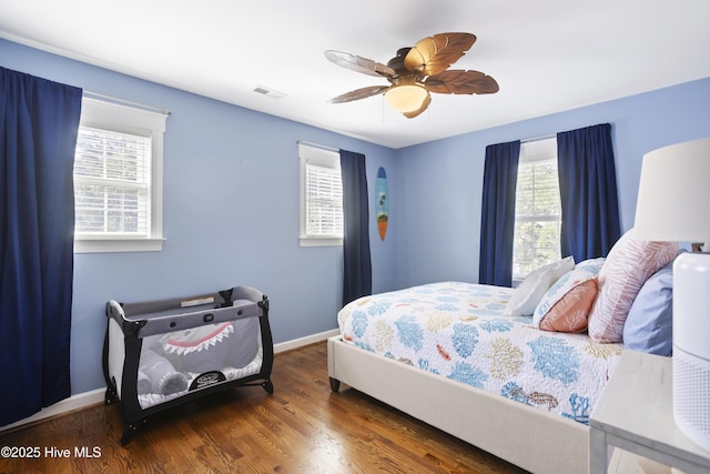 bedroom with ceiling fan, wood finished floors, visible vents, and baseboards