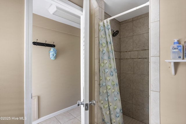 bathroom featuring tile patterned flooring, a tile shower, and baseboards