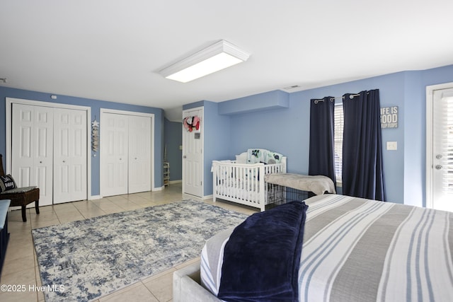 bedroom with tile patterned flooring, two closets, and baseboards