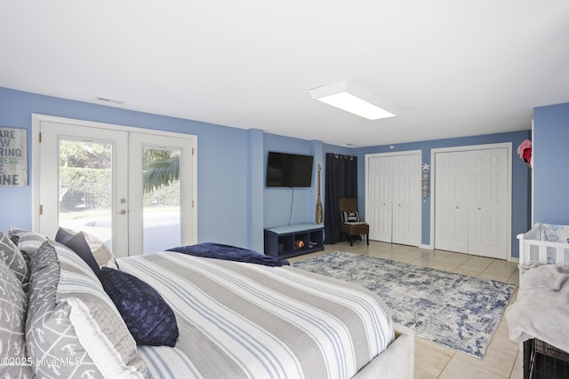 bedroom featuring french doors, two closets, light tile patterned floors, visible vents, and access to outside