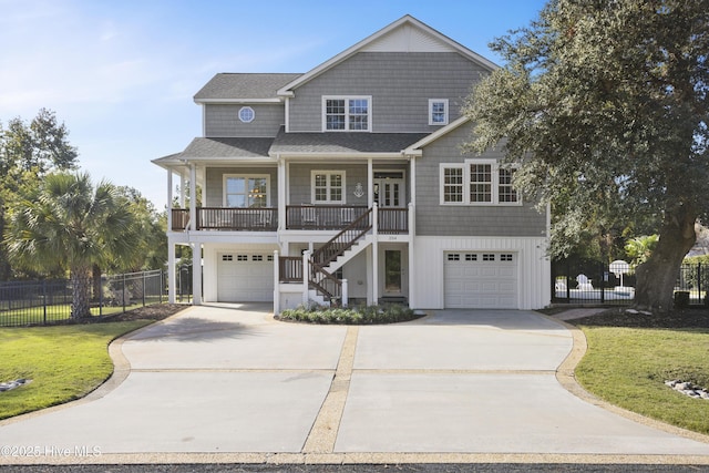 beach home featuring a porch, a garage, concrete driveway, stairway, and a front lawn