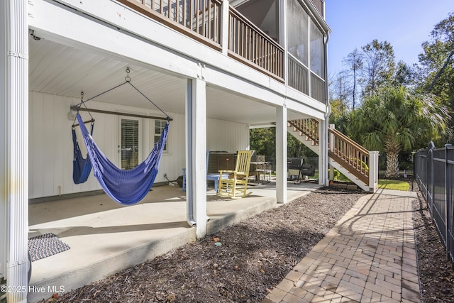 view of patio / terrace featuring stairs, fence, and a sunroom