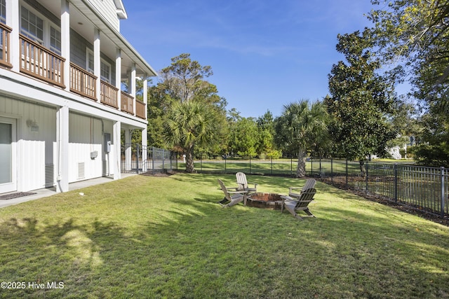 view of yard with an outdoor fire pit, a fenced backyard, and a balcony