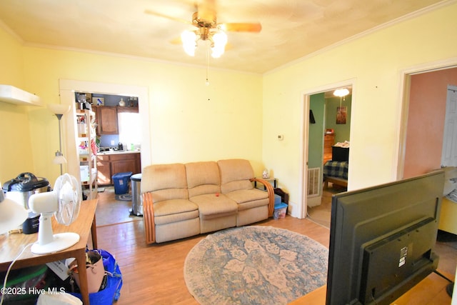 living room with crown molding, ceiling fan, and light hardwood / wood-style floors