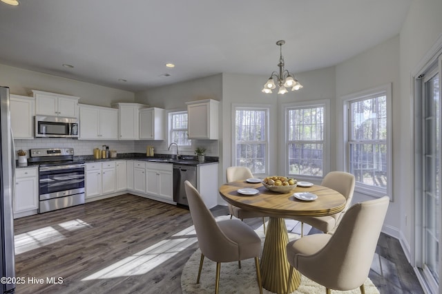 kitchen with decorative light fixtures, sink, white cabinetry, and stainless steel appliances