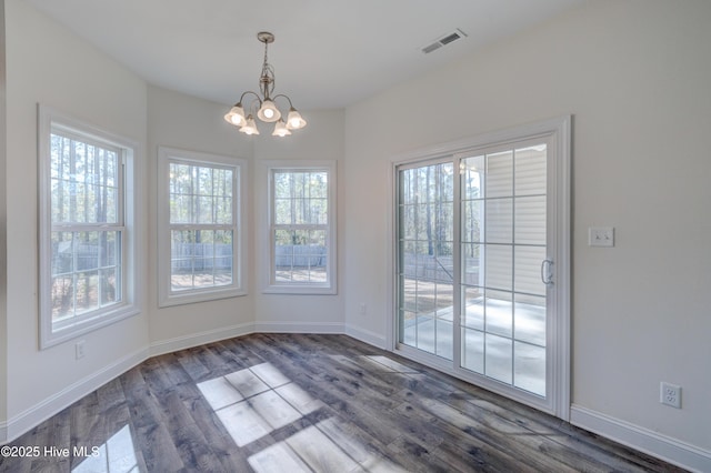 unfurnished dining area with dark hardwood / wood-style flooring and a chandelier