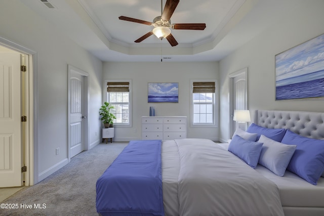 bedroom with a tray ceiling, multiple windows, ceiling fan, and light carpet