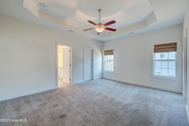 unfurnished bedroom with connected bathroom, ceiling fan, a raised ceiling, light colored carpet, and ornamental molding