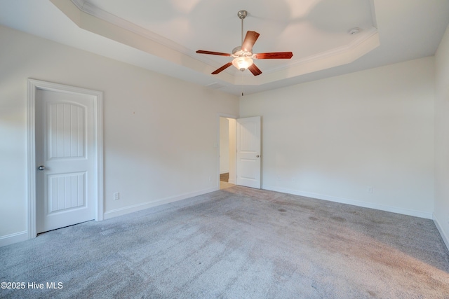 carpeted spare room with a tray ceiling, ceiling fan, and crown molding