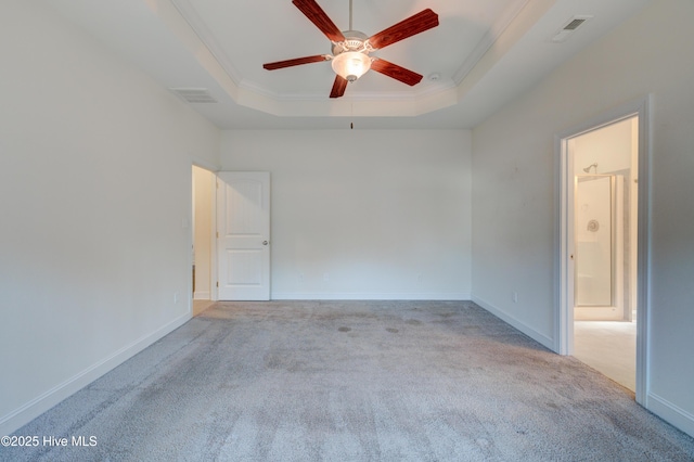 empty room with light colored carpet, a raised ceiling, ceiling fan, and ornamental molding