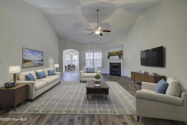 living room featuring hardwood / wood-style floors, ceiling fan with notable chandelier, and lofted ceiling