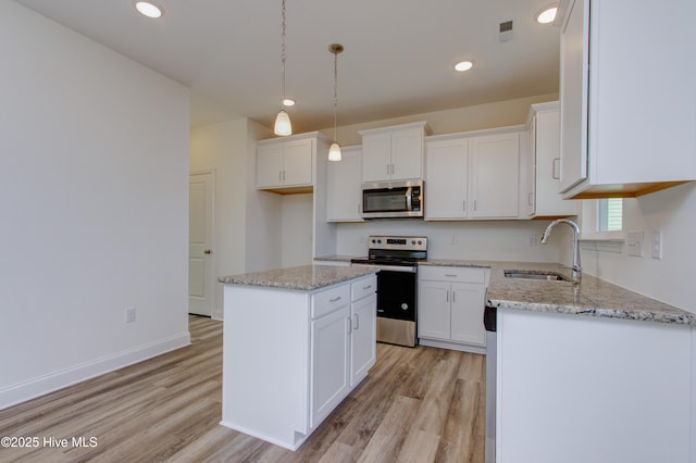 kitchen with sink, white cabinetry, appliances with stainless steel finishes, a kitchen island, and pendant lighting